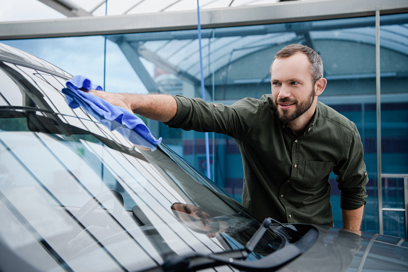 Man wiping the car wind shield with a cloth.
